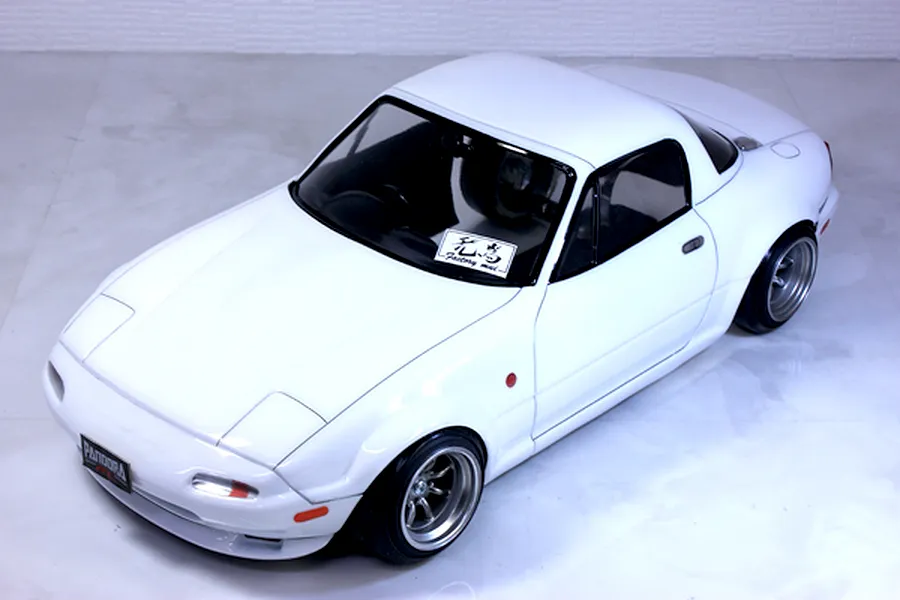 White Mazda Eunos Roadster NA RC drift car body shell mounted on a chassis with custom wheels against a neutral background.