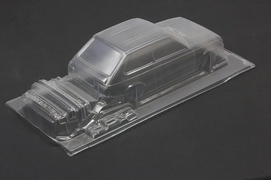 Unpainted clear polycarbonate RC car body shell for Toyota Starlet KP61 on a dark surface.