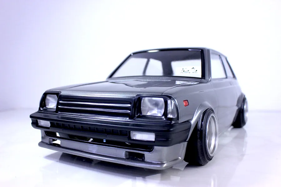Front three-quarter view of a grey RC drift car body mounted on a chassis against a plain white background.