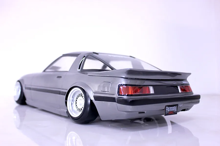 Rear three-quarter view of a silver Mazda Savanna RX-7 RC drift car body shell with deep dish wheels on a white background.