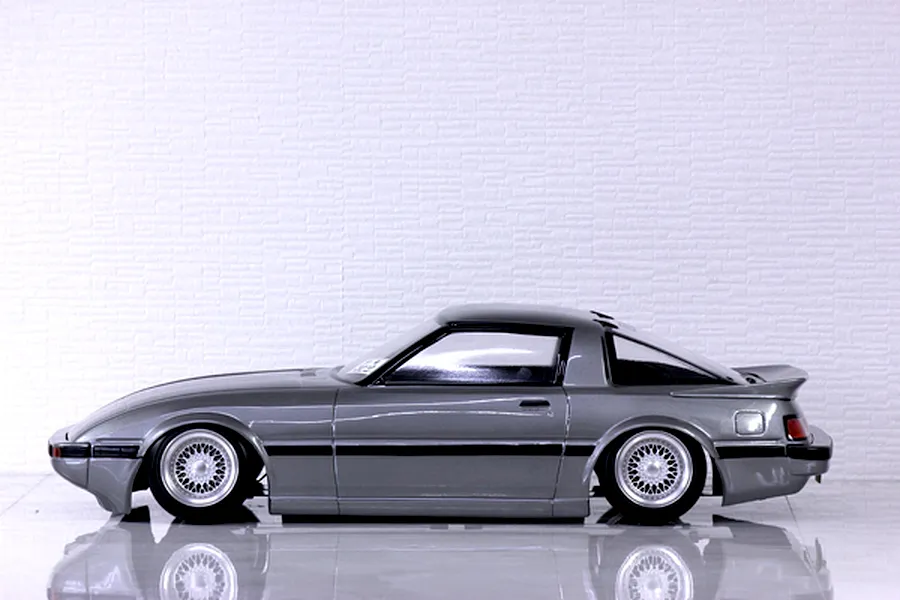 Side profile of a grey Pandora RC Mazda Savanna RX-7 SA22C body shell mounted on an RC chassis with wire-mesh wheels.