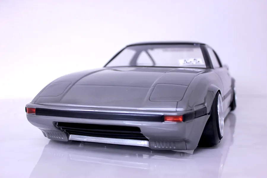 Low angle front view of a grey Mazda Savanna RX-7 SA22C RC drift car body shell with gloss finish and black bumper trim.