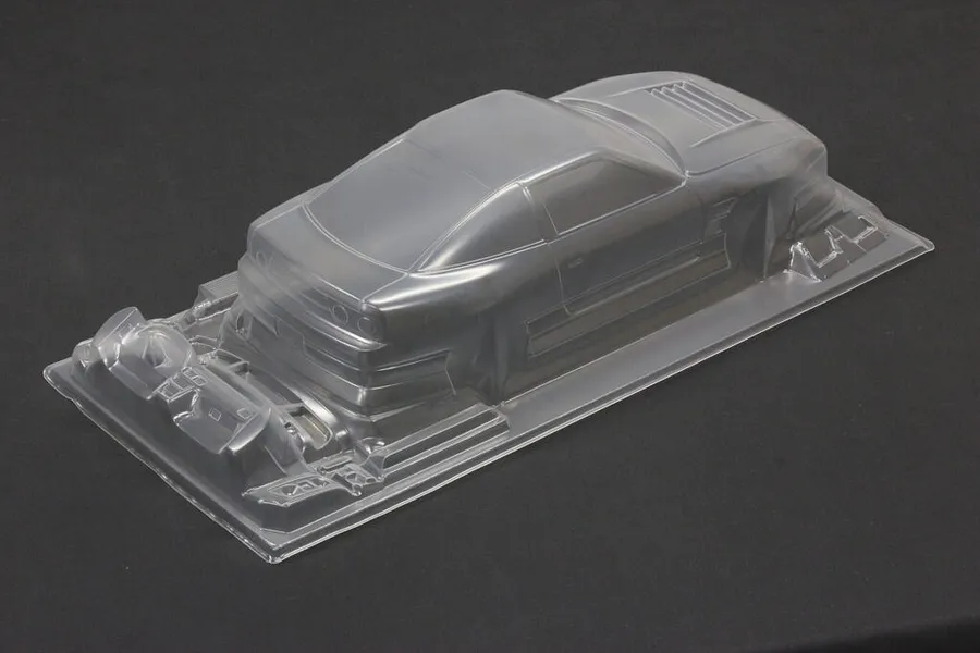 Unpainted clear polycarbonate RC drift car body shell viewed from the rear three-quarters on a dark surface.
