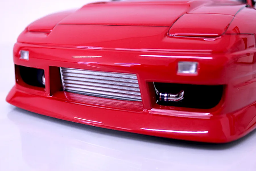 Close-up front view of a red RC drift car body showing the front bumper, pop-up headlight outlines, and a detailed intercooler.