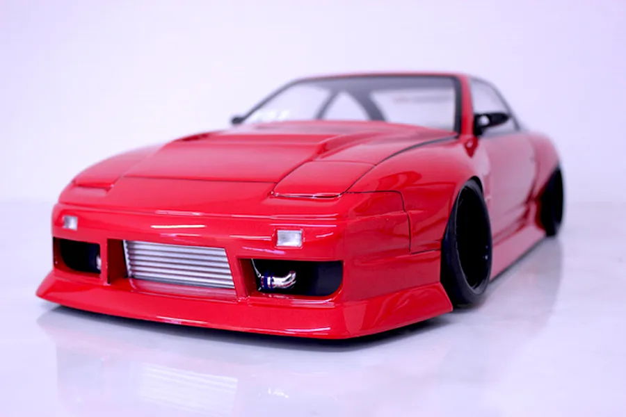Low angle front view of a red Pandora RC Nissan 180SX body shell with detailed front bumper, intercooler, and black wheels on a white studio background.