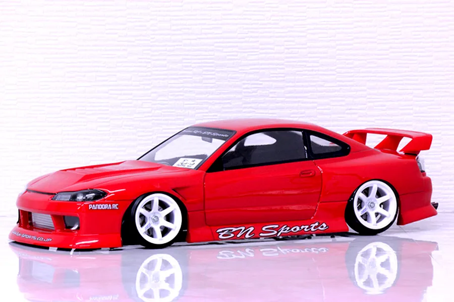Side profile of a painted red Pandora RC S15 Silvia BN Sports body shell on a white reflective surface.