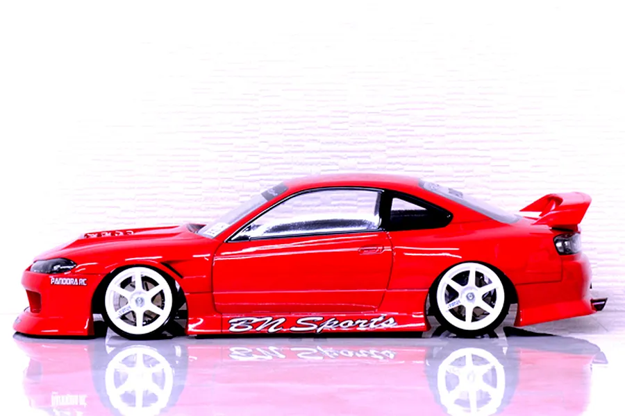Side profile view of a painted red Pandora RC S15 Silvia BN Sports body shell on an RC car with white wheels against a white background.