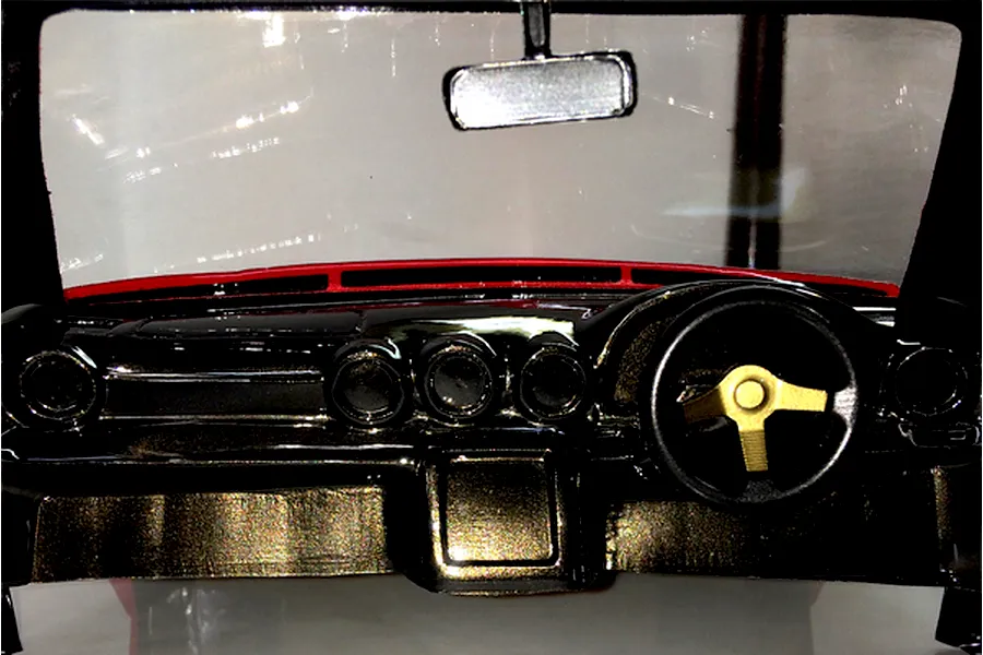 Close-up of a detailed RC car interior dashboard with a steering wheel and rearview mirror inside a transparent body shell.