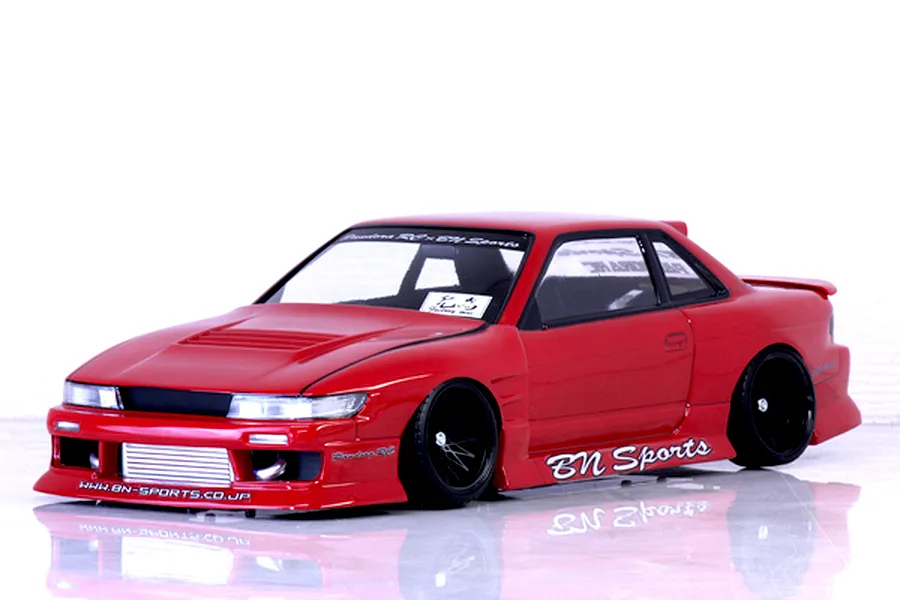Red Pandora RC S13 Silvia BN Sports drift body shell mounted on a chassis with black multi-spoke wheels, shown on a white reflective surface.