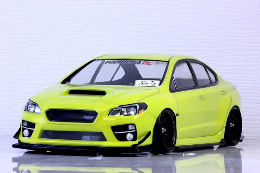 Lime green Subaru WRX STI RC drift car body shell displayed on a reflective surface against a white brick wall background.