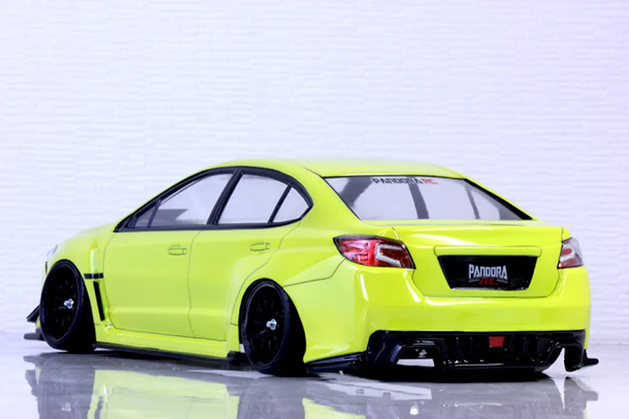 Rear-three-quarter studio view of a yellow Subaru WRX STI RC drift car body shell on black wheels against a white wall.