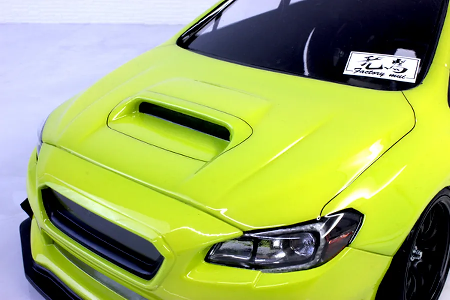 Close-up front angle view of a bright green RC car body featuring a prominent hood scoop and detailed headlights.