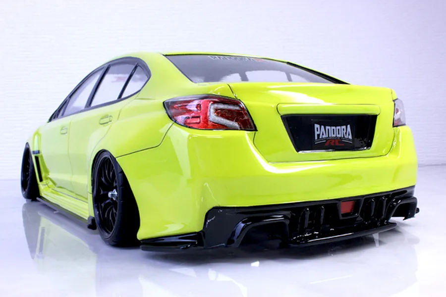 Rear-three-quarter view of a bright yellow RC drift car body shell mounted on a chassis with black wheels against a white studio background.