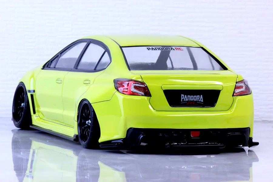 Rear-three-quarter view of a bright yellow RC drift car body shell representing a Subaru WRX STI with black wheels and aggressive body kit.