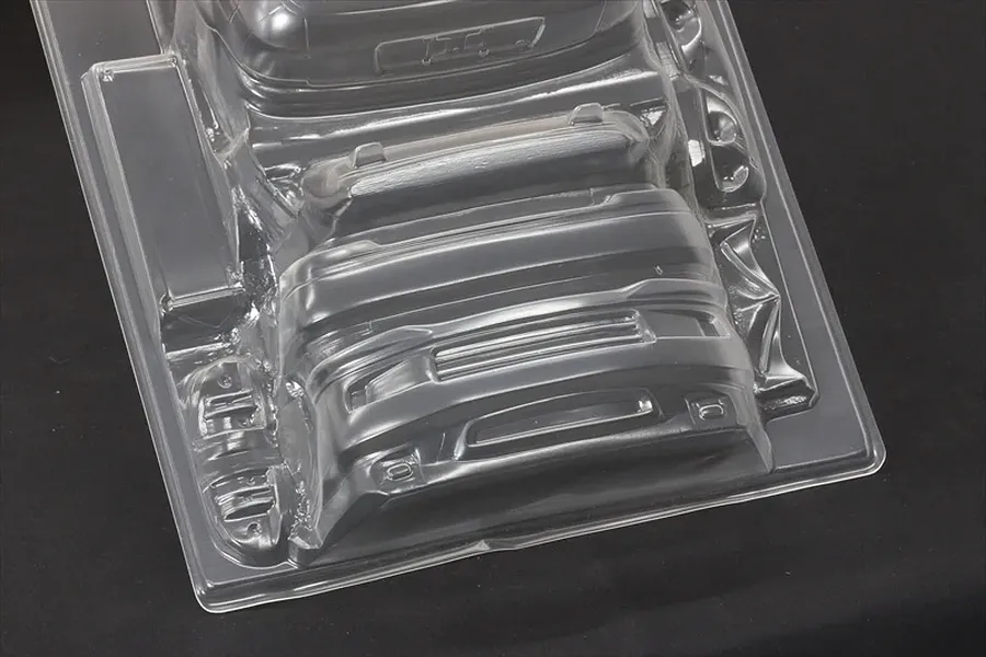Unpainted clear polycarbonate RC car body accessories and bumper parts on a black background.