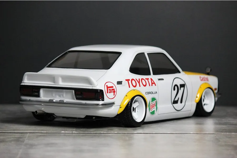 Rear three-quarter view of a painted Toyota Corolla Levin TE27 RC body shell in white with racing decals and white wheels.