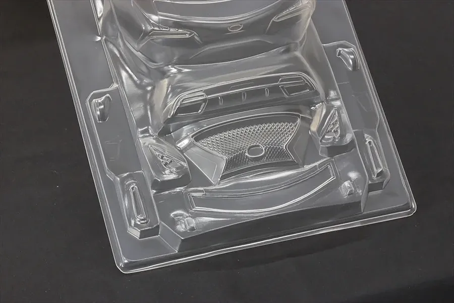 Unpainted clear polycarbonate RC car body accessories and parts molded on a single sheet against a dark background.