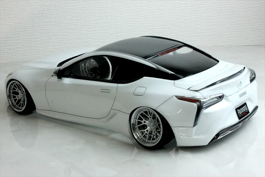 Rear-three-quarter view of a painted white RC drift car body with a black roof and custom wheels.