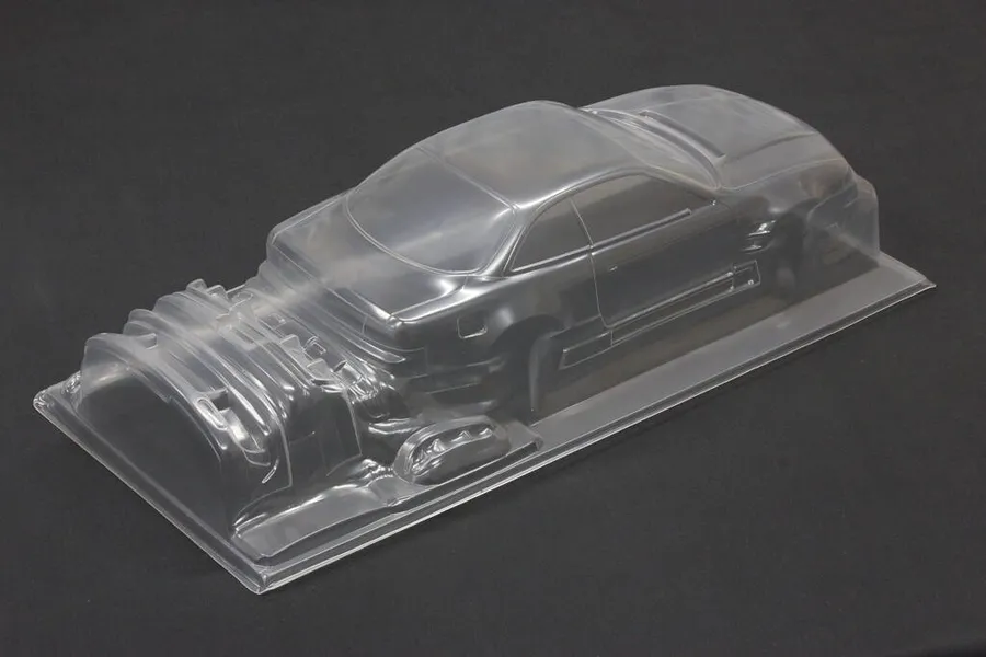 Unpainted clear polycarbonate RC drift car body shell sitting on a dark surface.