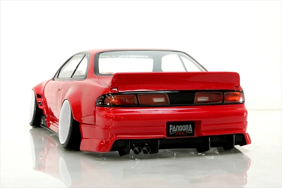Rear three-quarter view of a painted red RC drift car body shell mounted on a chassis with white wheels and dual exhaust tips.