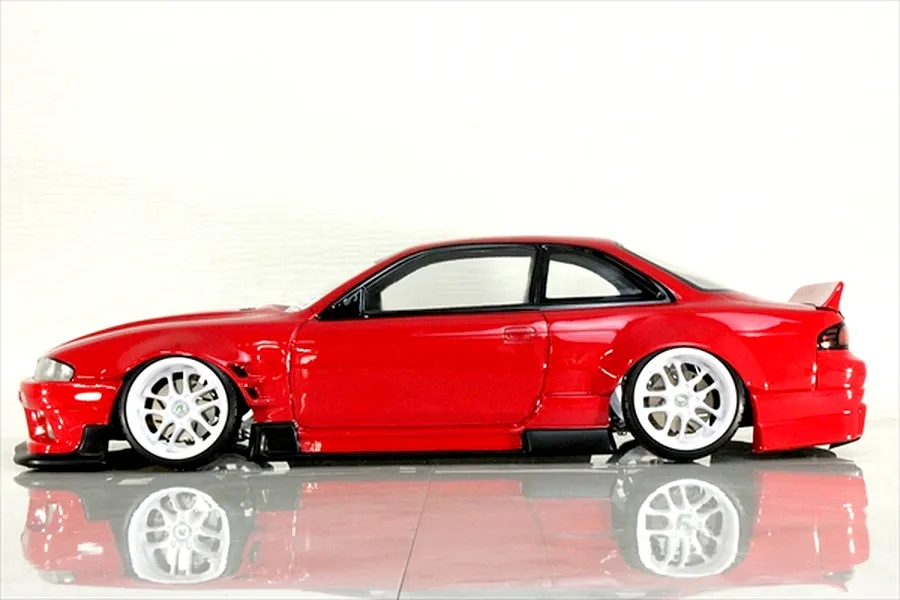 Side profile view of a red RC drift car body shell mounted on a chassis with white wheels against a white background.