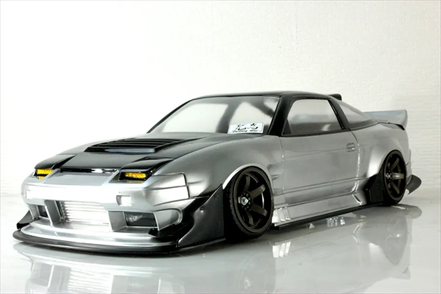 Silver and black RC drift car body shell styled after a customized Nissan 180SX parked on a reflective white studio surface.