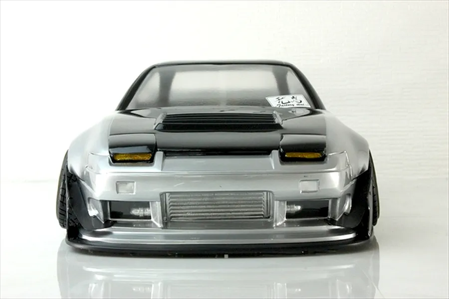 Front view of a silver and black RC drift car body shell with pop-up headlights and front intercooler.