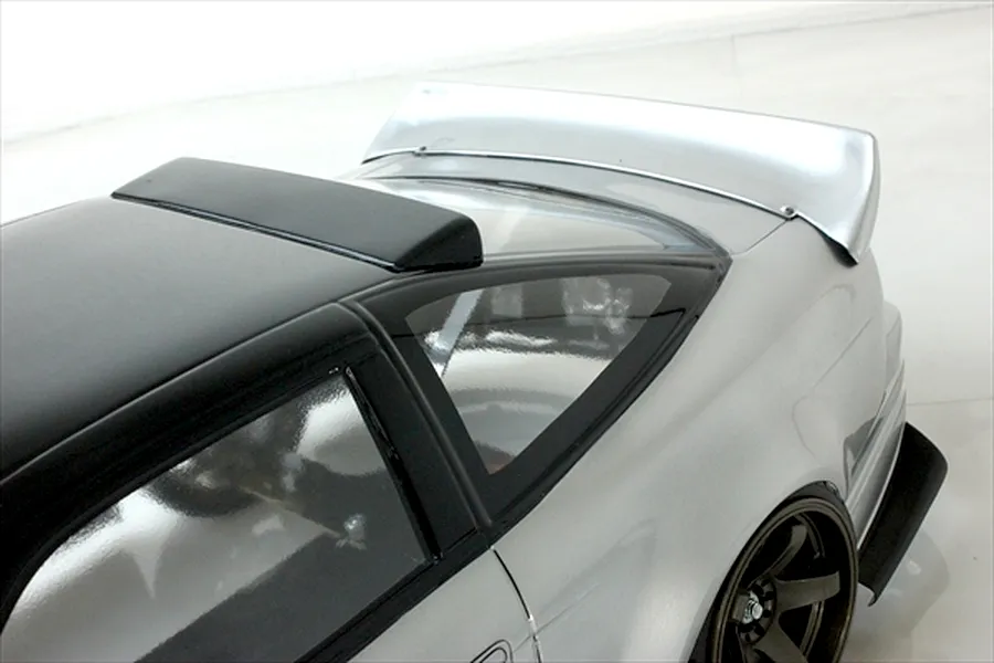 High angle close up of the roof, rear window, and spoiler on a silver and black RC drift car body.