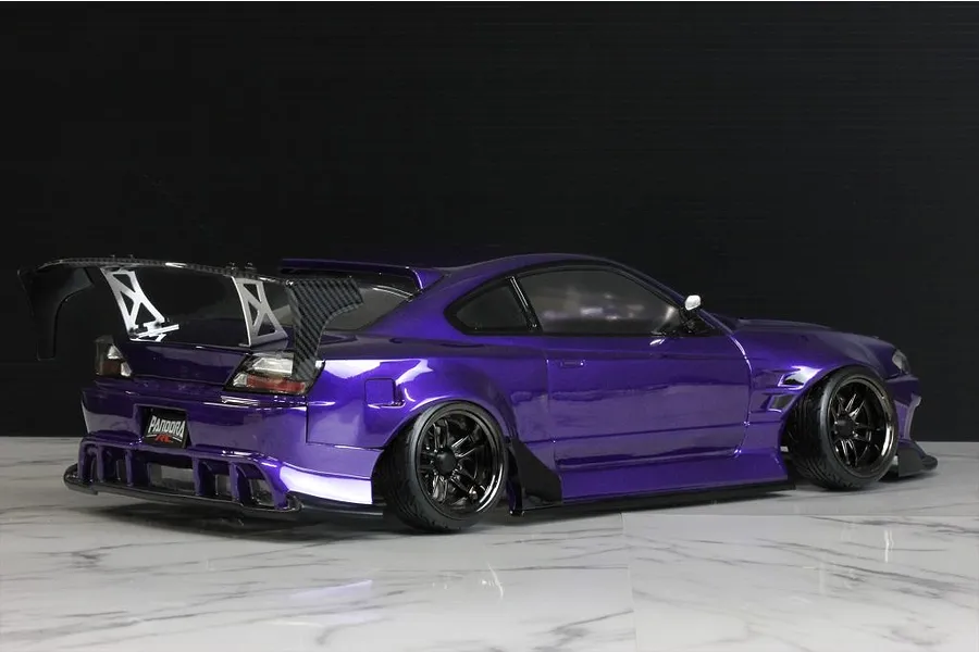 Rear three-quarter view of a metallic purple RC drift car body styled like a Nissan S15 Silvia with large rear wing and black wheels.