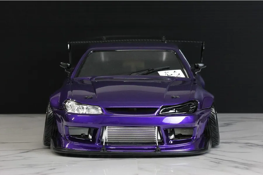 Front view of a purple RC drift car body shell with a detailed intercooler and aggressive styling on a marble surface.