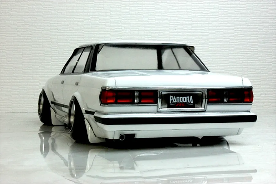Rear view of a white RC drift car body showing detailed tail lights, bumper, exhaust, and Pandora RC license plate against a textured background.