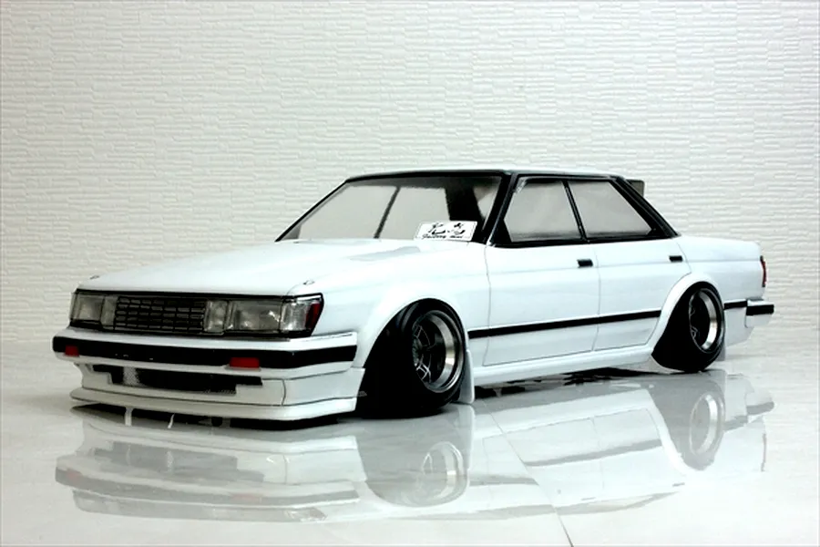 A painted white RC drift car body shell mounted on a chassis with custom wheels against a textured background.