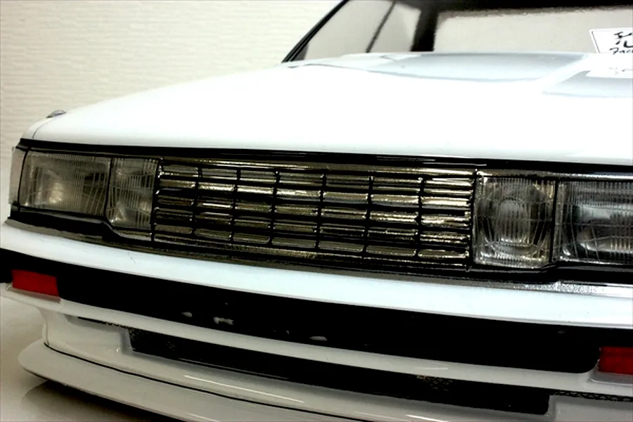 Close-up front view of a white RC car body shell showing the grille, headlights, and bumper detail.