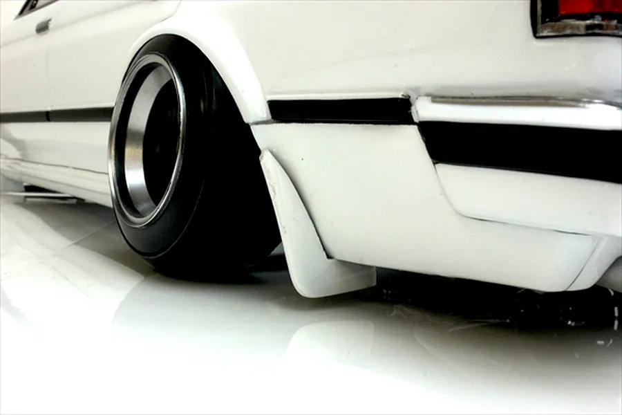 Close-up of the rear quarter section and wheel of a white RC drift car body with a deep dish wheel and mudflap.