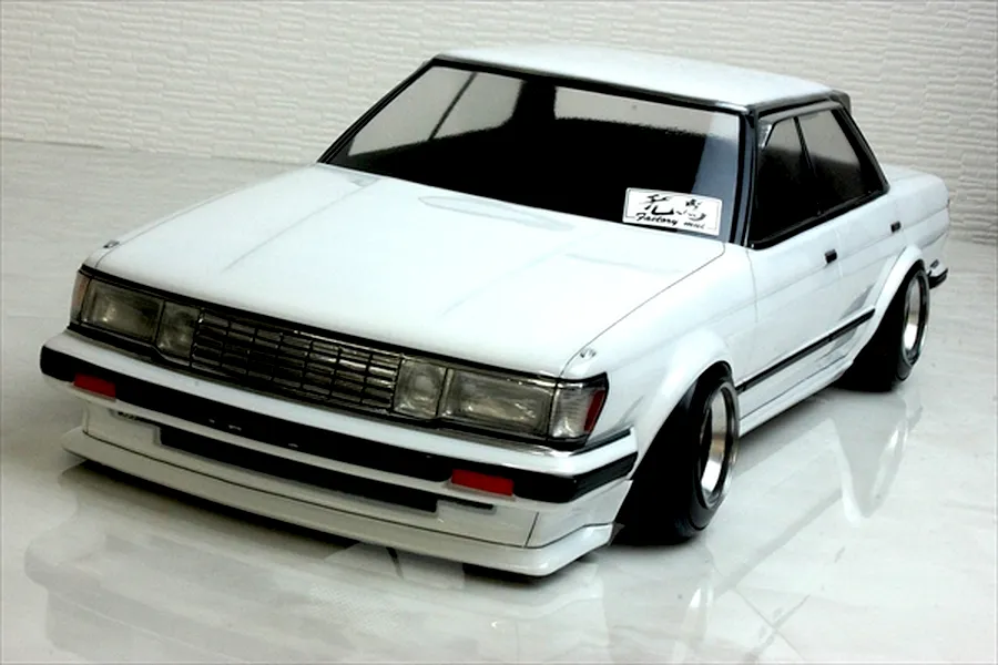 Painted white Toyota Mark 2 GX71 RC drift car body shell mounted on a chassis with custom wheels against a tiled background.