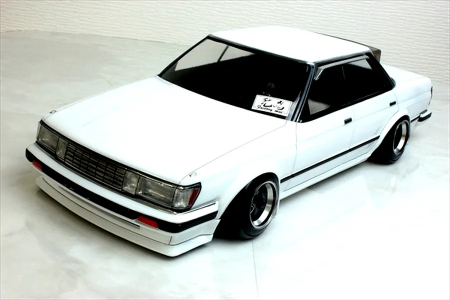 White Toyota Mark 2 GX71 RC drift car body shell mounted on a chassis with custom wheels against a light surface.