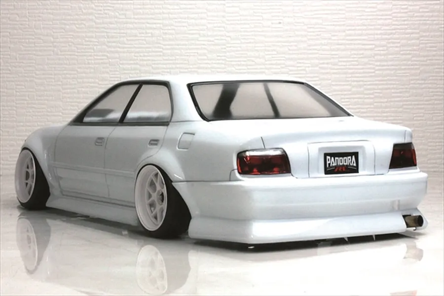 Rear three-quarter view of a white RC drift car body shell with deep dish white wheels and a Pandora RC license plate against a textured background.