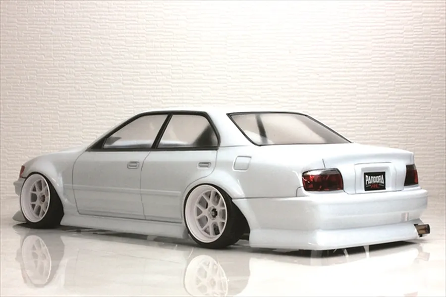 Rear three-quarter view of a white Toyota Chaser JZX100 RC drift car body shell on a reflective white studio surface.