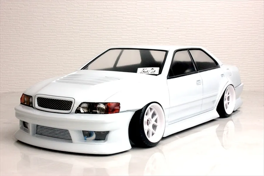 White Toyota Chaser RC drift car body shell on a studio table with white textured background