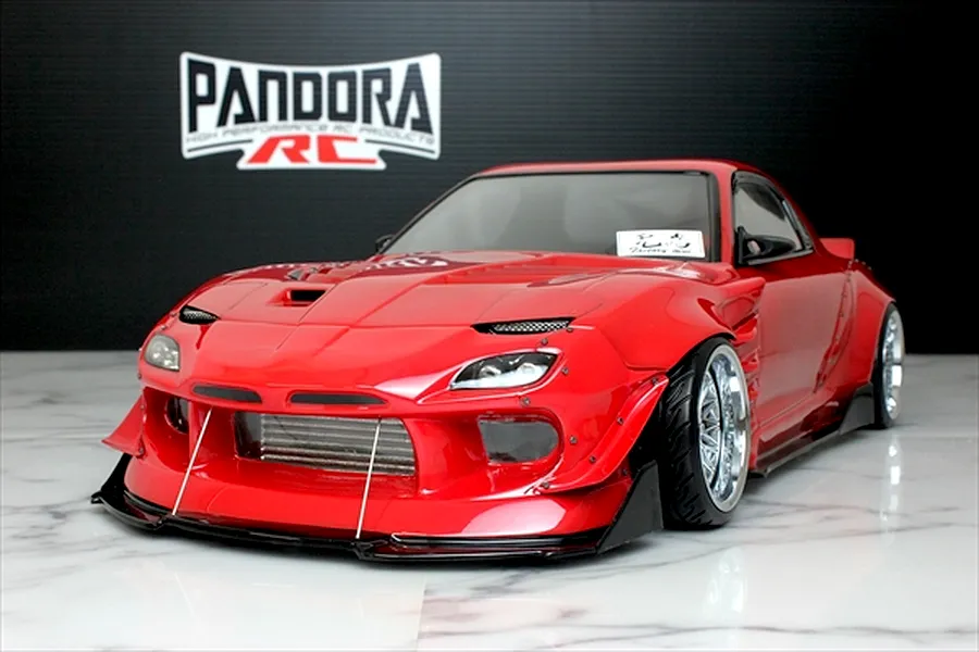 A red Pandora RC Mazda RX-7 FD3S RC drift car body shell with BN Sports styling displayed on a white marble surface in front of a black wall.