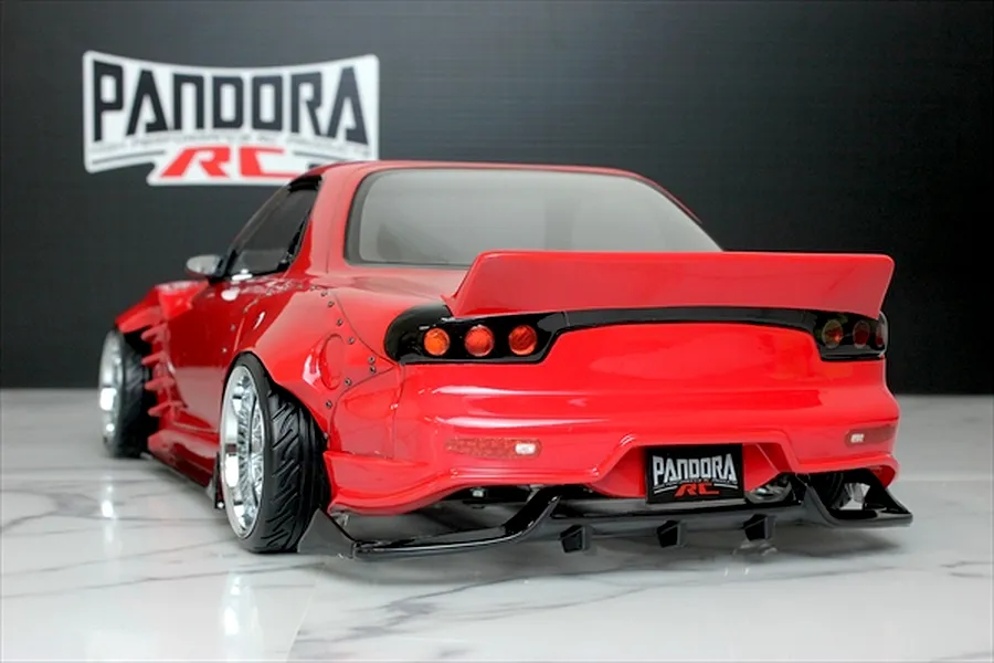 Rear three-quarter view of a red Pandora RC Mazda RX-7 FD3S RC body shell with a BN Sports kit, displayed on a marble surface.