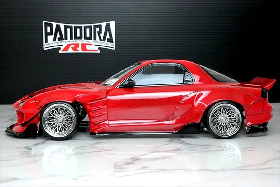 Side profile of a painted red Mazda RX-7 FD3S RC drift car body with BN Sports body kit and chrome mesh wheels.