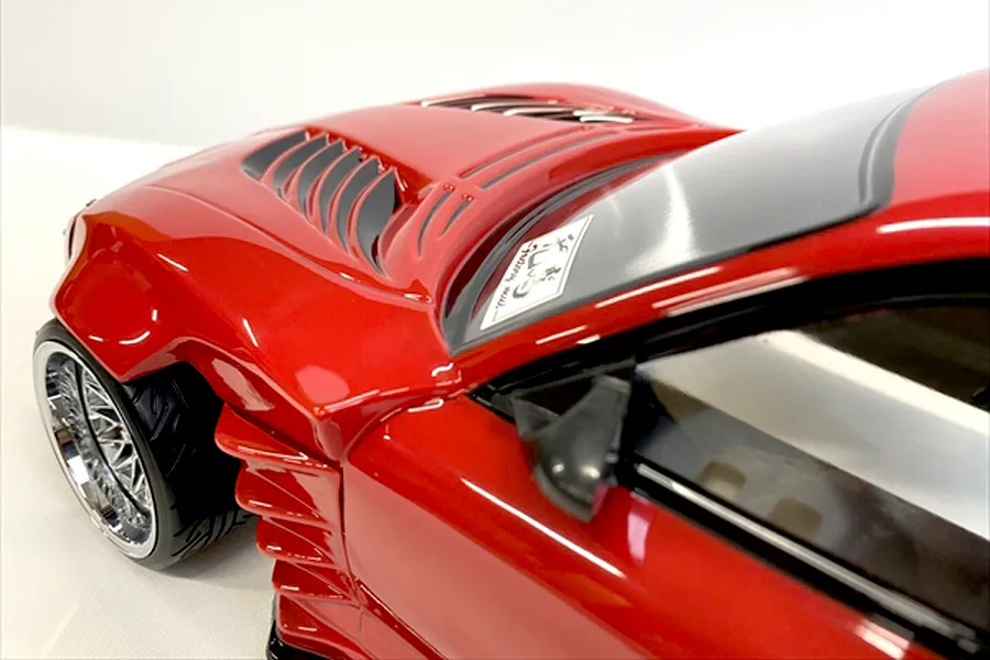 Close-up of the red painted bonnet, vented louvres, front fender, and front wheel of the Pandora RC Mazda RX-7 body shell.