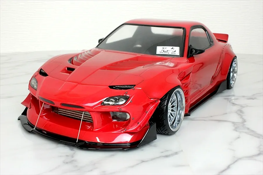 Red RC drift car body shell styled after a Mazda RX-7 FD3S with BN Sports widebody kit on marble surface.