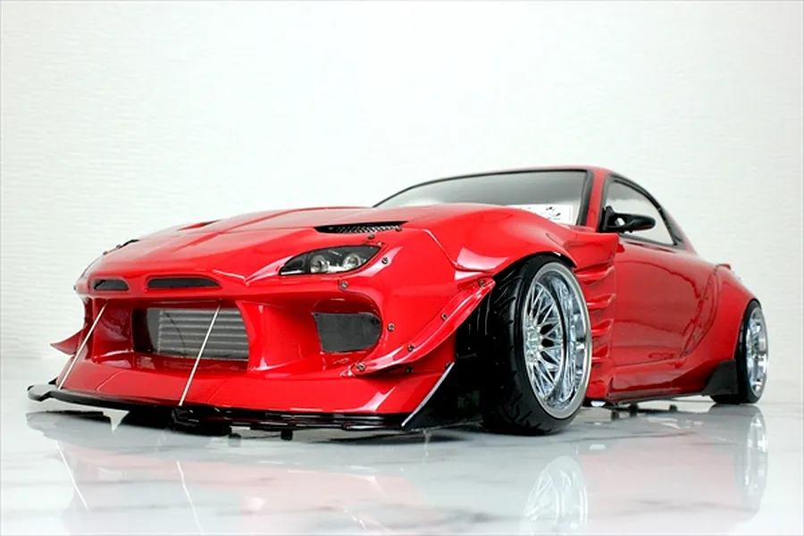 Red RC drift car body shell styled after a Mazda RX-7 FD3S with BN Sports widebody kit on a reflective white surface.