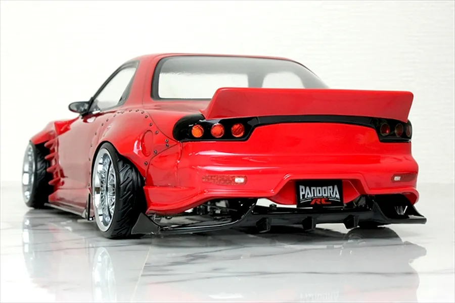 Rear three-quarter view of a red Pandora RC Mazda RX-7 FD3S drift body with wide fenders, rear spoiler, and black diffuser on a reflective surface.