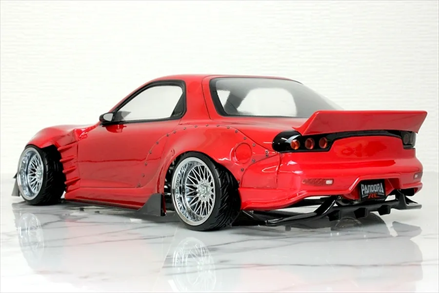 Rear three-quarter view of a red RC drift car body shell, specifically a Mazda RX-7 FD3S with wide fenders and a ducktail spoiler.