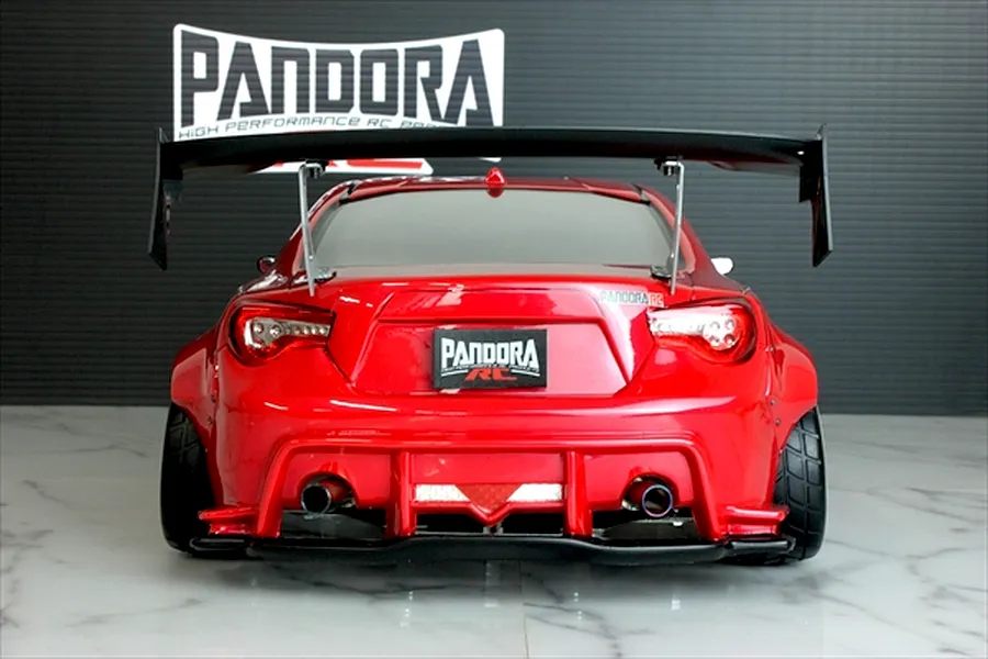Rear view of a red Pandora RC Toyota 86 body shell featuring a large black rear wing, dual exhaust tips, and wide fenders.