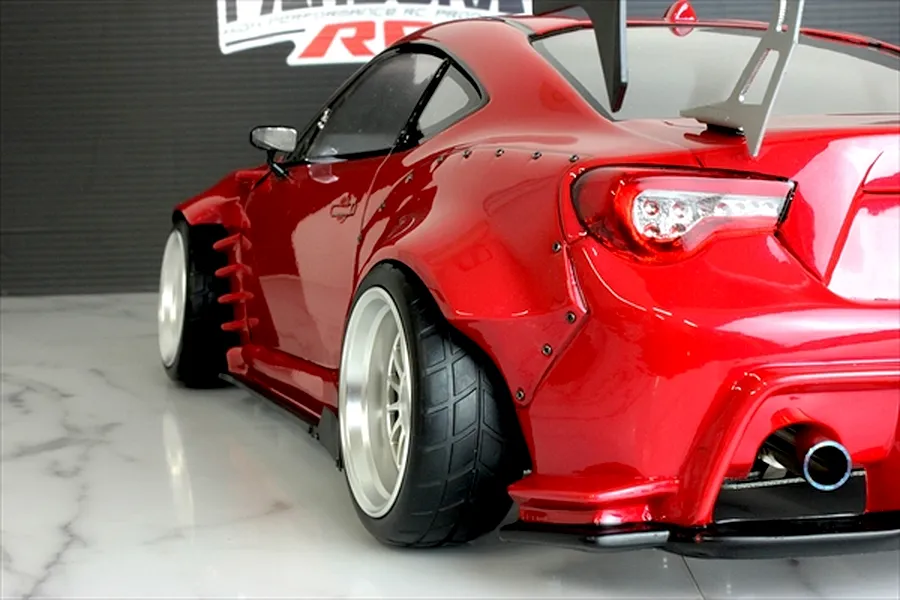 Rear three-quarter view of a red Pandora RC Toyota 86 body shell with wide fender flares, large rear wing, and deep dish wheels.