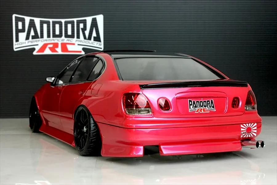 Rear three-quarter view of a painted red RC drift car body featuring black wheels, dual exhaust, and Pandora RC branding on a studio background.